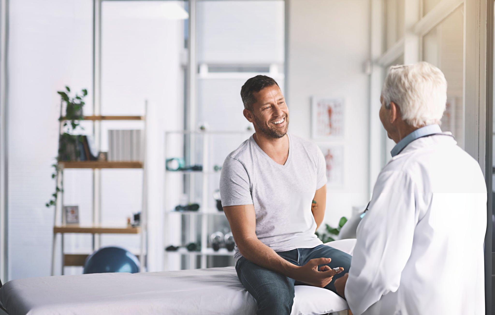 Smiling man consulting with doctor in modern clinic – reflecting Enerosora’s expert-backed approach to health and wellness for adults over 40